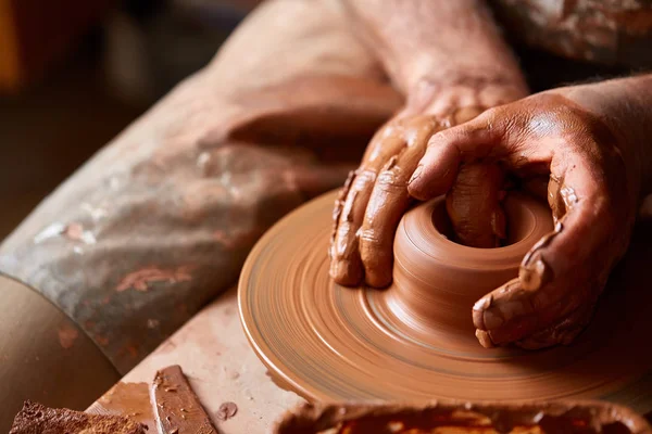 Gros plan mains d'un potier masculin dans un tablier faisant un vase d'argile, mise au point sélective — Photo