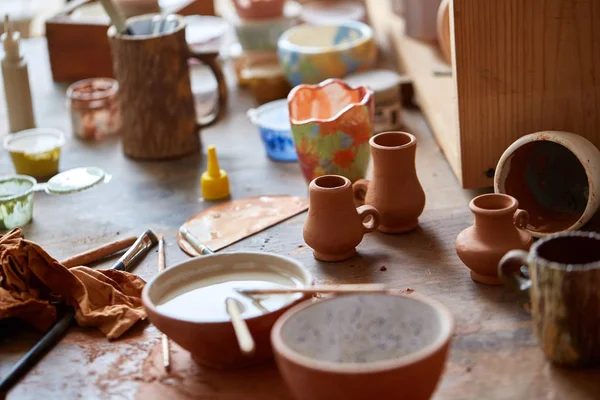 Close-up dari berbagai mug cat dan kuas pada tempat kerja, fokus selektif, tampilan samping . — Stok Foto