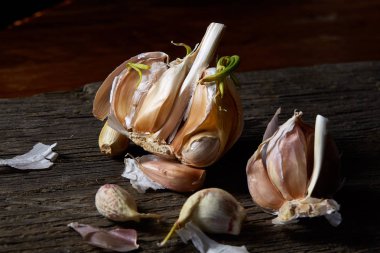 Sarımsak parçalar üzerinde karanlık kesme tahtası ahşap masa, sığ derinliği alan, seçici odak, makro yakın çekim