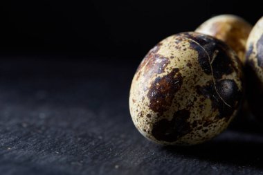 Bazı Bıldırcın yumurta bir koyu arka plan, üstten görünüm, yakın çekim, seçici odak grup, uzay kopyalayın, aydınlatma.