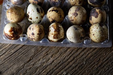 Bıldırcın yumurtası koyu ahşap arka plan, üstten görünüm, seçici odak plastik bir kap içinde