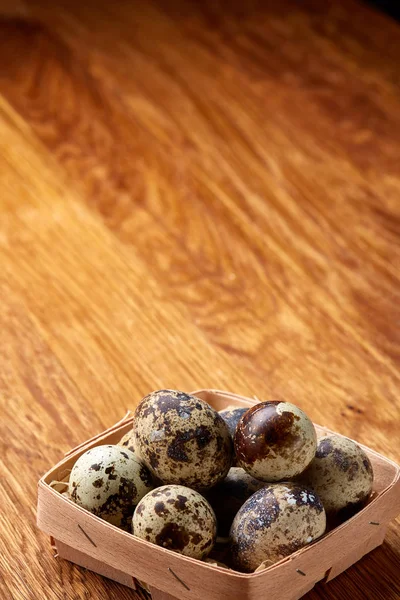 Vaktelägg i en ruta på en rustik trä bakgrund, ovanifrån, selektivt fokus, vertikal. — Stockfoto