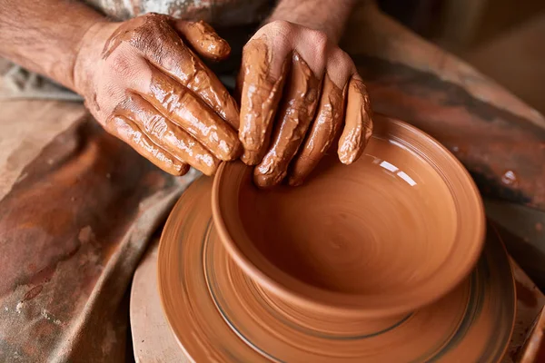 Close-up van de handen van een mannelijke potter in mallen schort kom uit klei, selectieve aandacht — Stockfoto