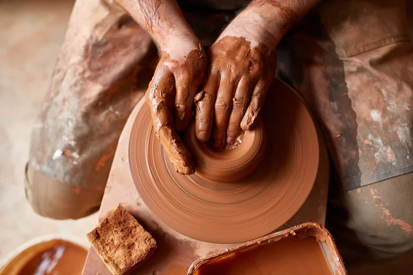 Крупним планом руки чоловічого гончаря в фартух формує чашу з глини, вибірковий фокус — стокове фото