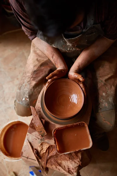 A male potter in apron molds bowl from clay, selective focus, close-up — Stock Photo, Image