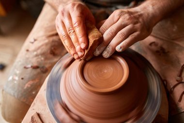 Yetişkin erkek potter usta kil plaka potters tekerlek üzerinde modelleme. Üstten Görünüm, portre, sadece eller.