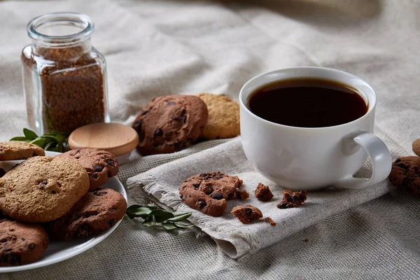 Kaffeetasse, Glas mit Kaffeebohnen, Kekse über selbstgesponnener Tischdecke, selektiver Fokus, Nahaufnahme, Draufsicht — Stockfoto