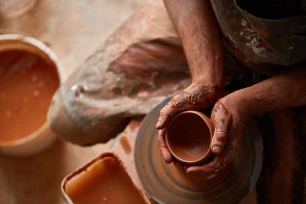 Close-up van de handen van een mannelijke potter in mallen schort kom uit klei, selectieve aandacht — Stockfoto