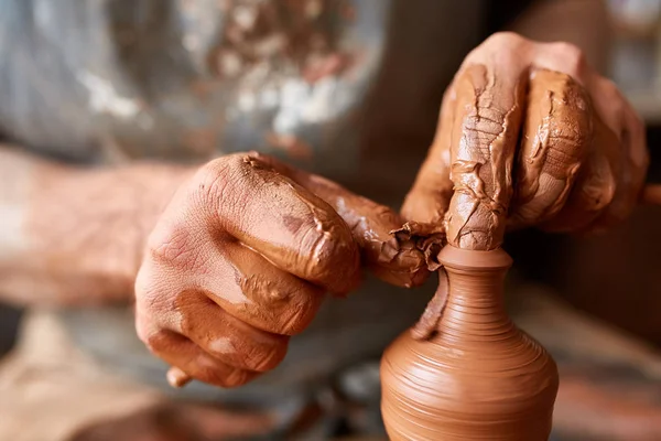 Close-up mãos de um oleiro macho em moldes de avental tigela de barro, foco seletivo — Fotografia de Stock