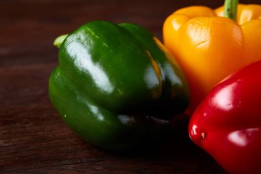 Taze organik yeşil, sarı ve kırmızı biber rustik ahşap zemin üzerine birleşimi.