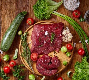 Natürmort ham sığır eti beyaz arka plan, üstten görünüm, seçici odak ahşap plaka üzerinde sebzeli