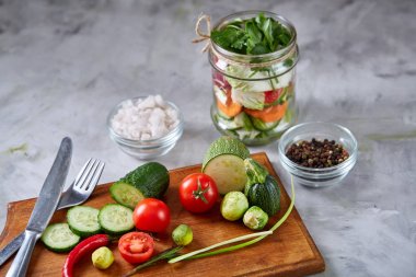 Kavanoz ve tablo, seçici odak, yakın çekim kesme tahtası üzerinde taze sebzeler lezzetli sebze salatası