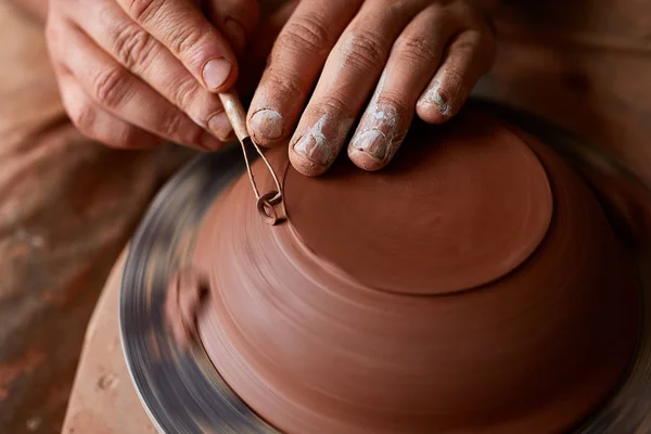 Volwassen mannelijke potter meester de kleiplaat modelleren op potters wiel. Bovenaanzicht, close-up, handen alleen. — Stockfoto