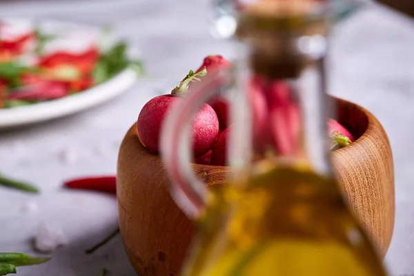 Złotej oliwy z oliwek w przezroczysty słoik przed płyta sałatka warzywo, płytkiej głębi ostrości — Zdjęcie stockowe