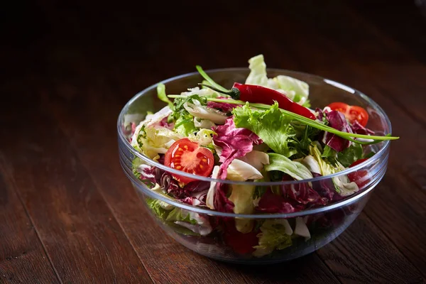 Salade de légumes frais servie dans un bol en verre sur fond de bois foncé, mise au point sélective, faible profondeur de champ — Photo