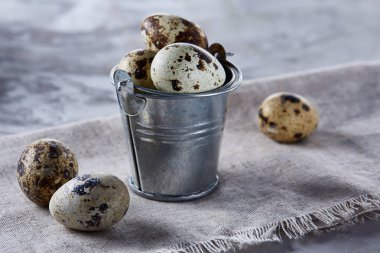 Küçük dekoratif kova peçete bıldırcın yumurtalarının dolu beyaz dokulu arka plan, yakın çekim, seçici odak üzerinde.