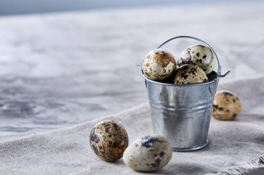 Küçük dekoratif kova peçete bıldırcın yumurtalarının dolu beyaz dokulu arka plan, yakın çekim, seçici odak üzerinde.