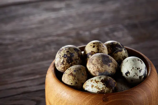 Verse kwarteleitjes in een houten kom op een donkere houten achtergrond, bovenaanzicht, close-up — Stockfoto