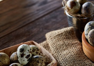 Bıldırcın yumurtası kova, kutu ve ıslak zeminde ahşap arka plan, seçici odak keten bir peçete ile rustik natürmort