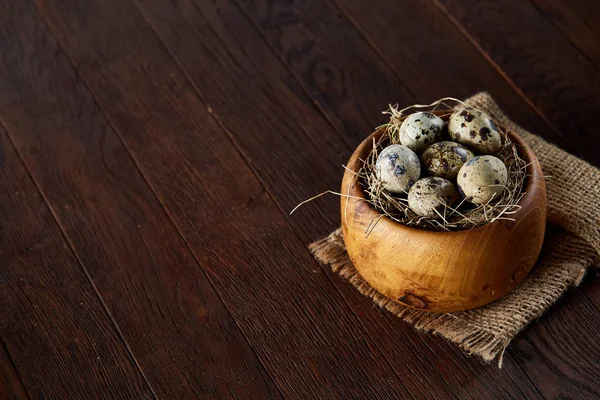 Huevos frescos de codorniz en un tazón de madera en una servilleta hecha en casa sobre fondo de madera oscura, vista superior, primer plano — Foto de Stock