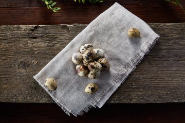 Piramit peçeteye Şimşir dalları ile düzenlenmiş bir ahşap masa, yakın çekim, seçici odak üzerinde bıldırcın yumurtası.