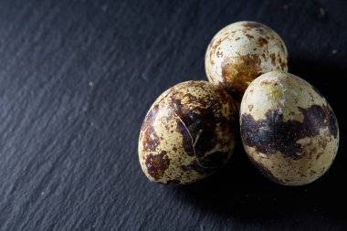 Bazı Bıldırcın yumurta bir koyu arka plan, üstten görünüm, yakın çekim, seçici odak grup, uzay kopyalayın, aydınlatma.