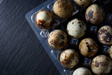 Bıldırcın yumurtası koyu ahşap arka plan, üstten görünüm, seçici odak, sığ derinlik-in tarla plastik bir kap içinde