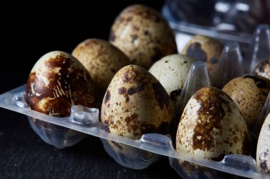 Bıldırcın yumurtası koyu ahşap arka plan, üstten görünüm, seçici odak, sığ derinlik-in tarla plastik bir kap içinde