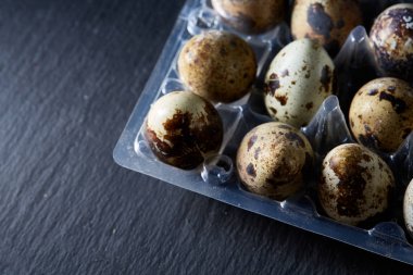 Bıldırcın yumurtası koyu ahşap arka plan, üstten görünüm, seçici odak, sığ derinlik-in tarla plastik bir kap içinde