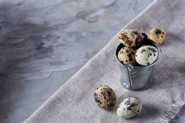 Küçük dekoratif kova peçete bıldırcın yumurtalarının dolu beyaz dokulu arka plan, yakın çekim, seçici odak üzerinde.