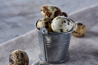 Küçük dekoratif kova peçete bıldırcın yumurtalarının dolu beyaz dokulu arka plan, yakın çekim, seçici odak üzerinde.