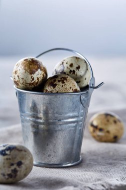 Küçük dekoratif kova peçete bıldırcın yumurtalarının dolu beyaz dokulu arka plan, yakın çekim, seçici odak üzerinde.