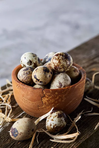 Bol en bois rempli d'œufs de caille sur planche de bois sur fond blanc, gros plan, mise au point sélective . — Photo