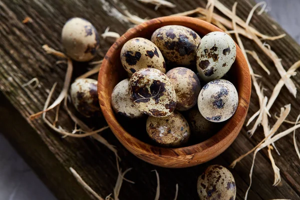 Bol en bois rempli d'œufs de caille sur planche de bois sur fond blanc, gros plan, mise au point sélective . — Photo