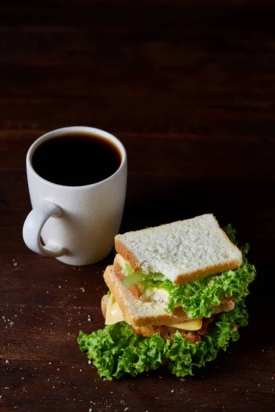 Breakfast table with sandwich and black coffee on rustic wooden background, close-up, selective focus — Stock Photo, Image