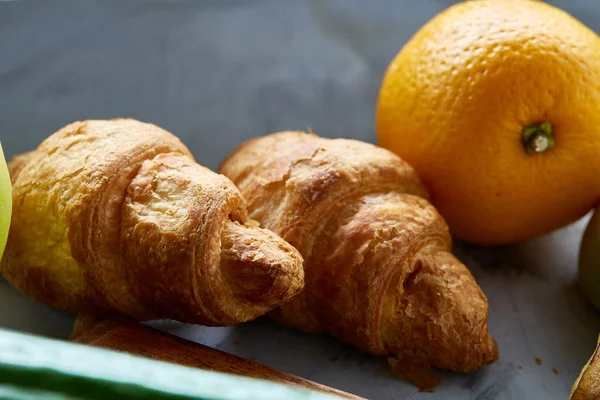 Frische leckere Croissants mit Apfel auf dunklem Schneidebrett, Nahaufnahme, selektiver Fokus — Stockfoto