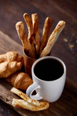 Kahve fincanı, breadsticks ve kruvasan bir eski ahşap arka plan, yakın çekim, seçici odak.