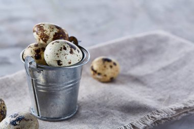 Küçük dekoratif kova peçete bıldırcın yumurtalarının dolu beyaz dokulu arka plan, yakın çekim, seçici odak üzerinde.