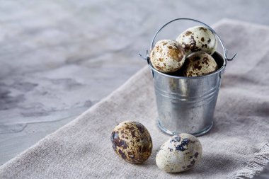 Küçük dekoratif kova peçete bıldırcın yumurtalarının dolu beyaz dokulu arka plan, yakın çekim, seçici odak üzerinde.