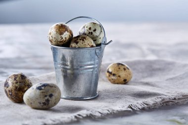 Küçük dekoratif kova peçete bıldırcın yumurtalarının dolu beyaz dokulu arka plan, yakın çekim, seçici odak üzerinde.
