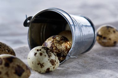 Küçük dekoratif kova peçete bıldırcın yumurtalarının dolu beyaz dokulu arka plan, yakın çekim, seçici odak üzerinde.