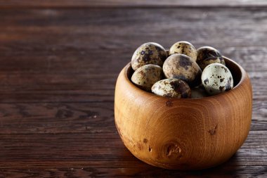 Bir koyu ahşap arka plan, üstten görünüm, yakın çekim bir ahşap kase taze bıldırcın yumurtası