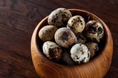 Bir koyu ahşap arka plan, üstten görünüm, yakın çekim bir ahşap kase taze bıldırcın yumurtası