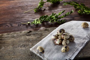 Piramit peçeteye Şimşir dalları ile düzenlenmiş bir ahşap masa, yakın çekim, seçici odak üzerinde bıldırcın yumurtası.