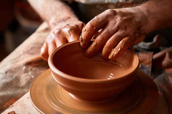 Een pottenbakker schildert een kleiplaat in een wit in de workshop, bovenaanzicht, close-up, selectieve focus. — Stockfoto