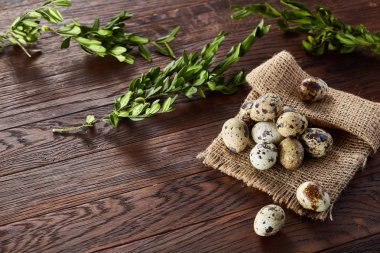 Piramit peçeteye Şimşir dalları ile düzenlenmiş bir ahşap masa, yakın çekim, seçici odak üzerinde bıldırcın yumurtası.