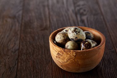 Koyu ahşap arka plan, üstten görünüm, yakın çekim saf peçeteye ahşap bir kase taze bıldırcın yumurtası