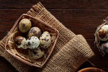 Bıldırcın yumurtası kova, kutu ve ıslak zeminde ahşap arka plan, seçici odak keten bir peçete ile rustik natürmort