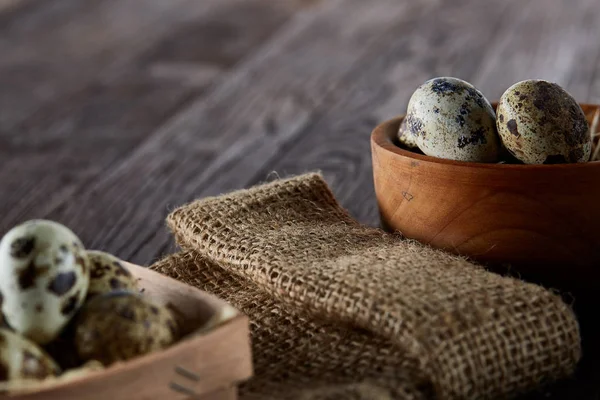 Nature morte rustique avec œufs de caille dans un seau, une boîte et un bol sur une serviette en lin sur fond en bois, mise au point sélective — Photo