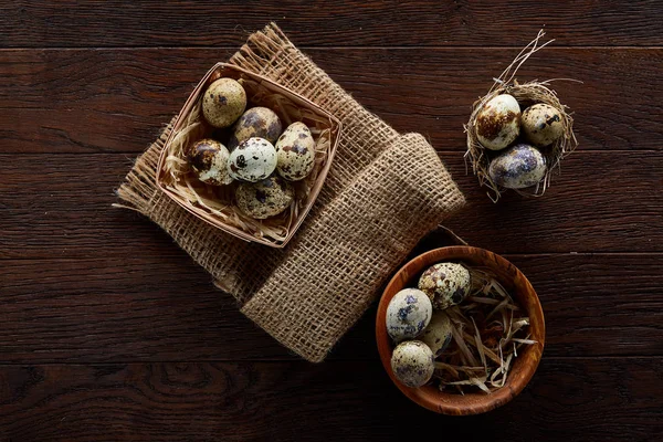 Bodegón rústico con huevos de codorniz en cubo, caja y tazón sobre una servilleta de lino sobre fondo de madera, enfoque selectivo — Foto de Stock